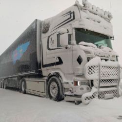 Camión grande con remolque azul y logotipo en carretera con nieve