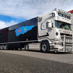 Camión blanco con remolque azul aparcado juntoi a nave